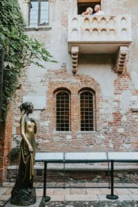Historic statue and Juliet's balcony in Verona, Italy attracts visitors.