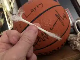basketball net, autographed basketball, hand holding piece of net