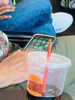 Have it Your Way - TruFlex Media Person resting a hand on their lap while holding a smartphone; a Burger King cup with a red straw sits in the foreground on a table or lap.