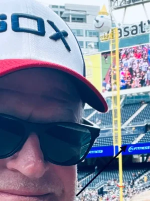 Jack On The Pole - TruFlex Media Close-up selfie of a person wearing a white cap with blue lettering and dark sunglasses at a crowded baseball stadium.