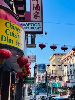 Chinatown, San Francisco - TruFlex Media Busy Chinatown street with red lanterns and colorful signs advertising Chinese cuisine and seafood restaurant under a blue sky, storefronts on both sides.