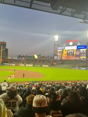 Oracle Park at Night - TruFlex Media Evening baseball game at a packed stadium, fans in the stands, players on the infield, and a scoreboard with ads in the outfield.
